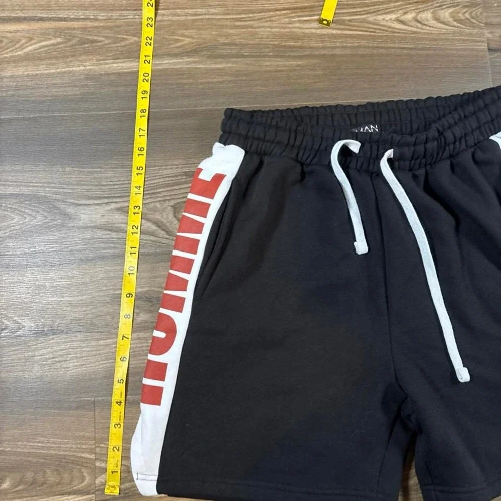 BoohooMAN black shorts with white side panels and red 'HOMME' text, size M